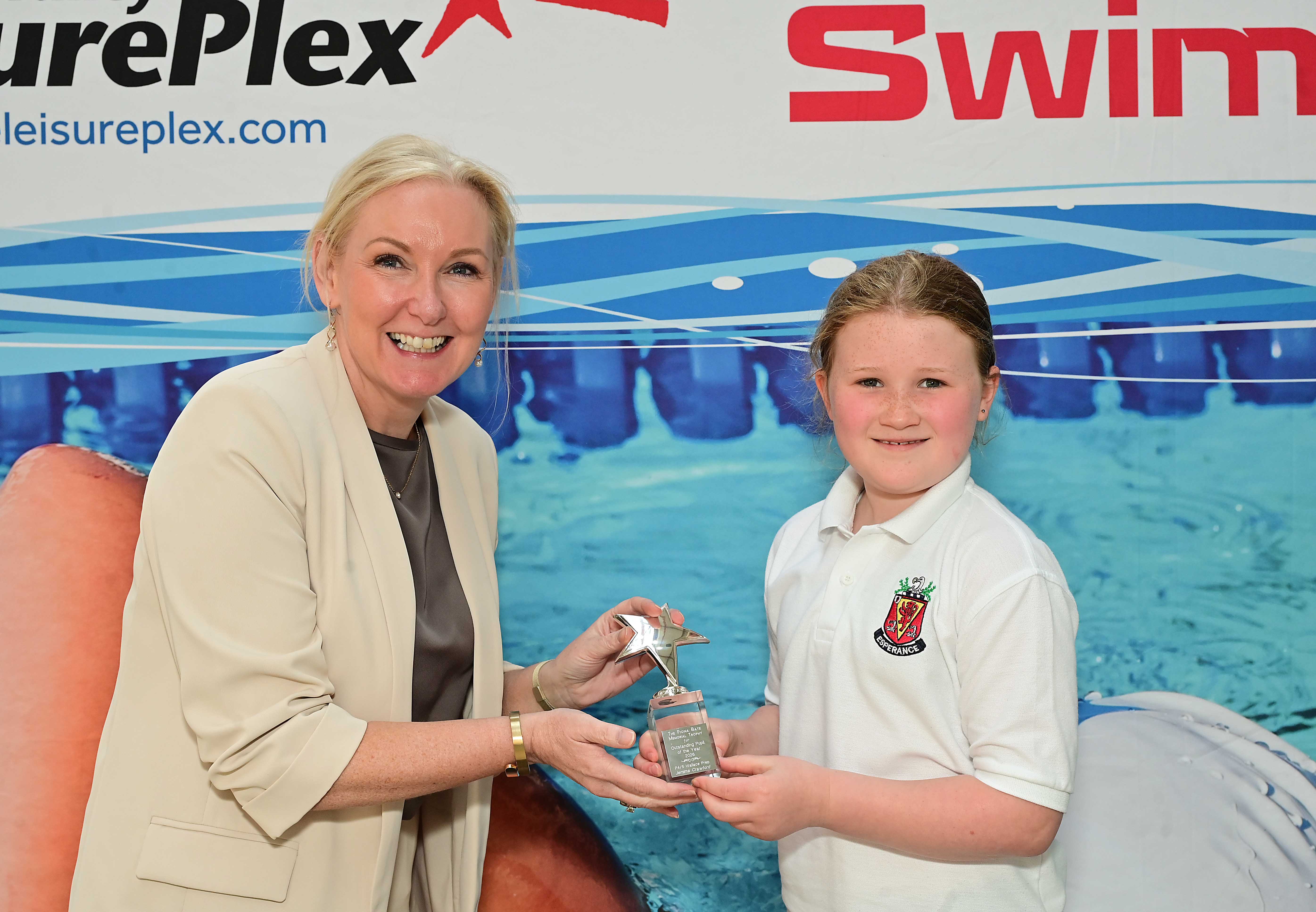  Louise Moore, Director of Leisure & Community Wellbeing presents the P4–P5 Fiona Bates Memorial Special Achievement Award to Jemima Crawford of Wallace Prep. 