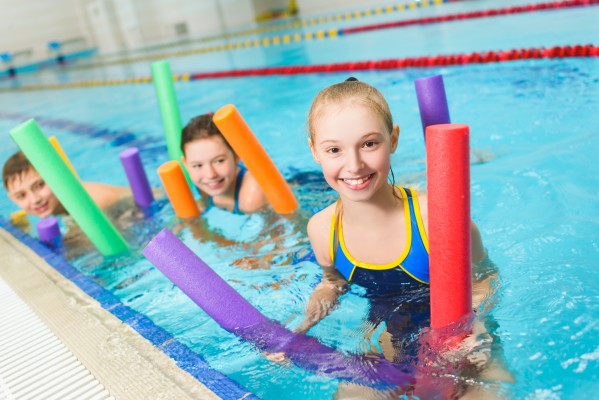 Two girls in swimming pool with water noodles