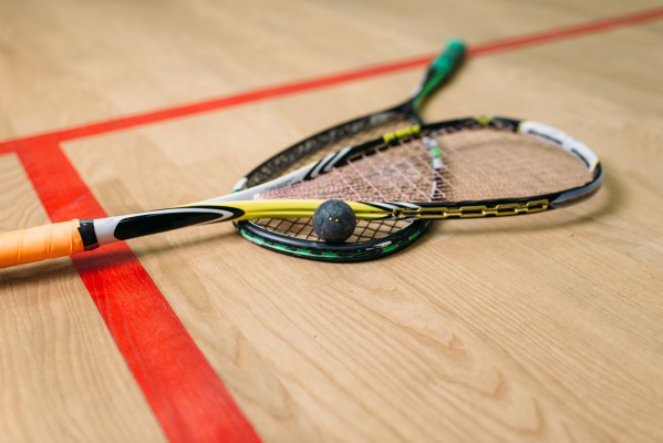 Two squash racquets with ball on squash court 