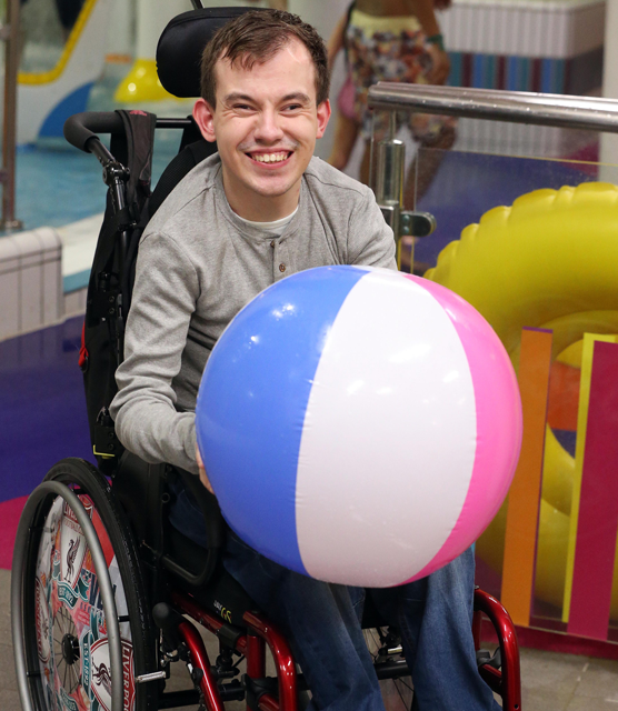 Boy in wheelchair holding beach ball